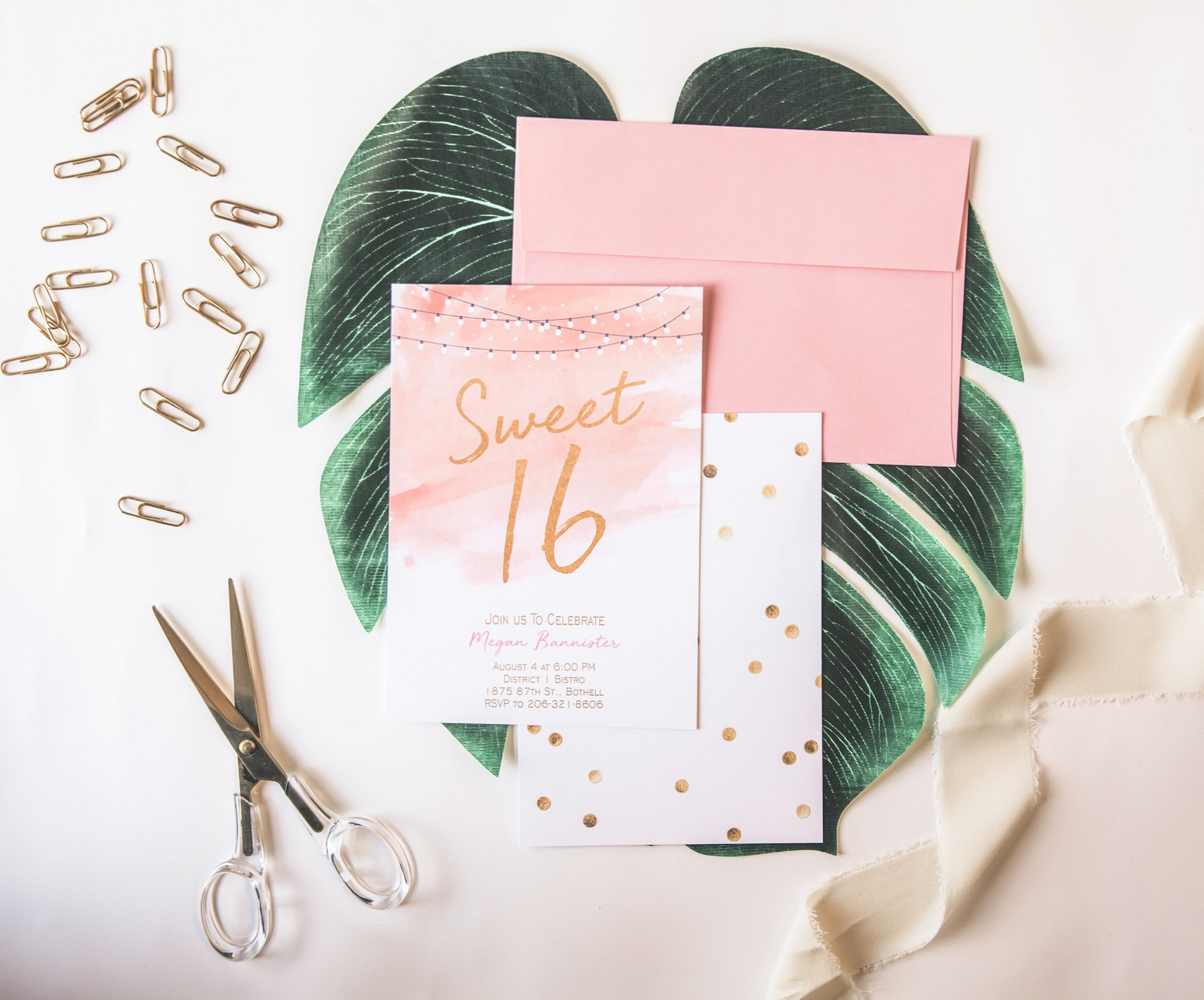 Girls Sweet 16 birthday invite with soft pink watercolor and string lights, displayed on a palm leaf