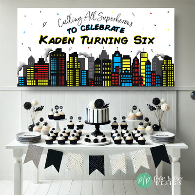 Superhero party banner with Comic book city skyline in front of a white and black dessert table