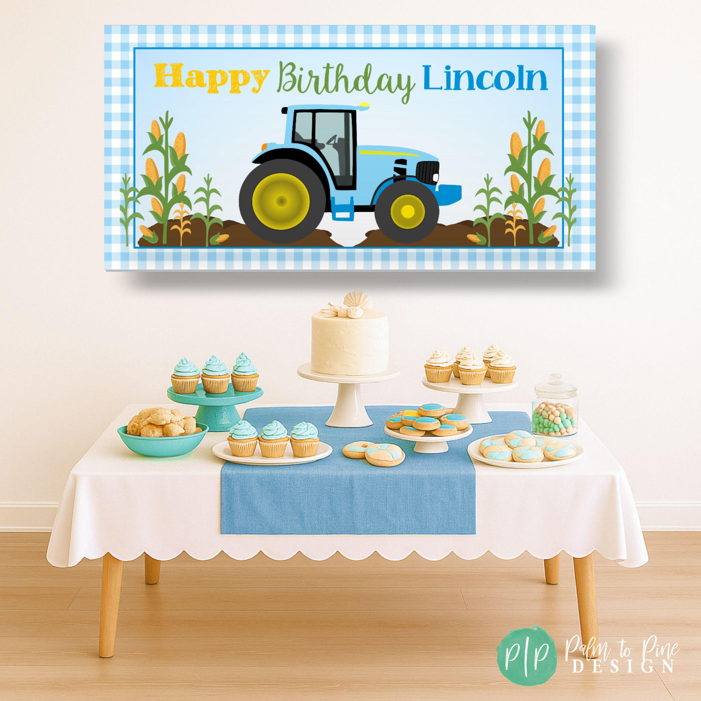Farm-themed boys birthday banner with blue tractor, gingham border, and wheat stalks hanging behind a dessert table at a country-style celebration