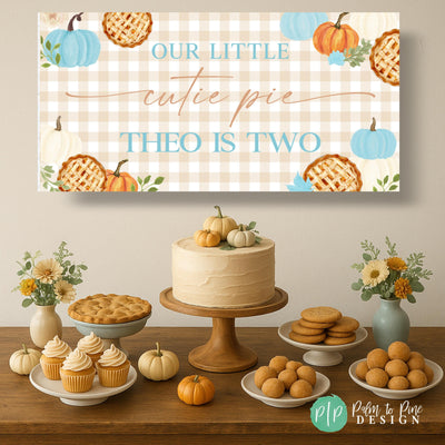 rustic our little cutie pie birthday banner in tan gingham with orange and baby blue pumpkins and pie clipart behind fall themed dessert table with rustic desserts and fall flowers and pumpkins