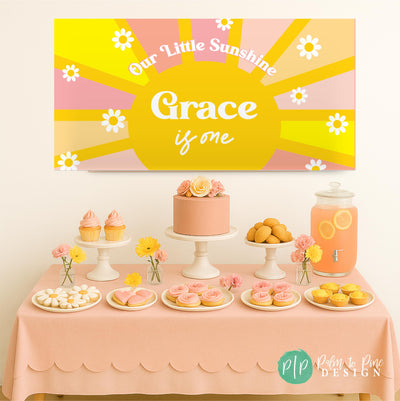 Our Little Sunshine birthday banner with yellow sun, pink and tan rays, and daisies, personalized with birthday girl’s name, displayed above a themed dessert table
