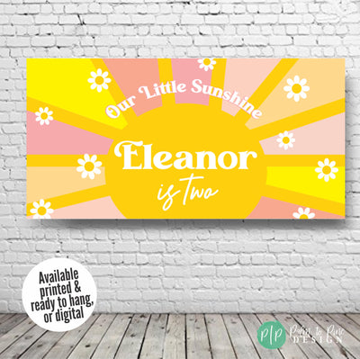 Personalized Our Little Sunshine birthday banner with a cheerful yellow sun, multicolored rays, and daisies, shown against a plain white wall