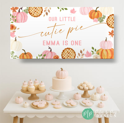 Our Little Cutie Pie Pumpkin themed birthday banner for girls with fall leaves and florals set behind a light pink pumpkin themed dessert table