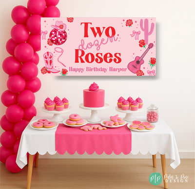 Pink and red Two Dozen Roses birthday banner featuring western and rope fonts, cowgirl and musical icons, displayed behind a themed dessert table for a girls’ birthday party.