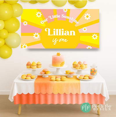 Girls’ Our Little Sunshine party banner with sun and daisy design, personalized text, staged behind a pink and yellow dessert table with cupcakes and treats.