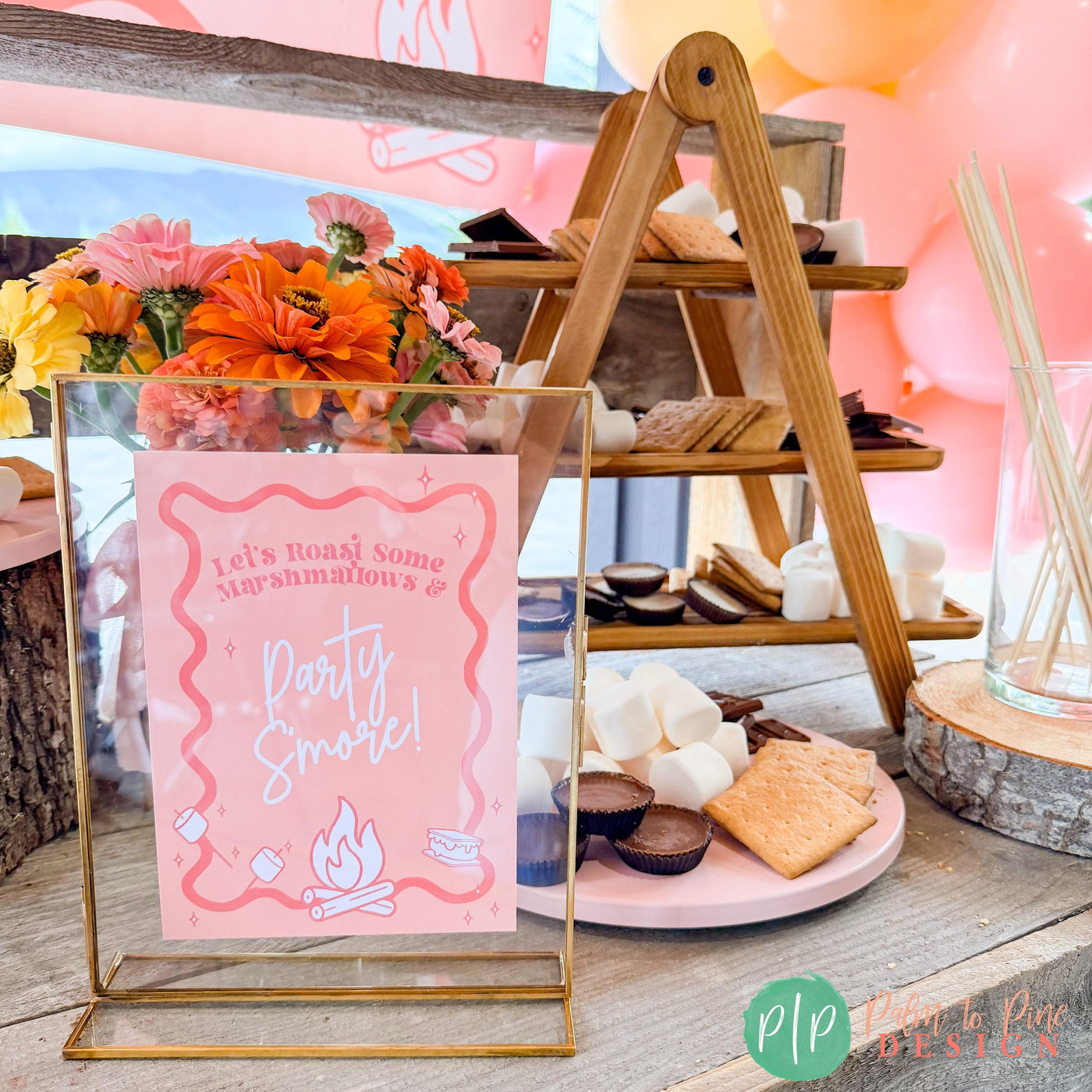 Pink S&#39;mores Bar with Party Sign in gold frame and marshmallows, graham crackers, Reese&#39;s and Hershey&#39;s bars in the background