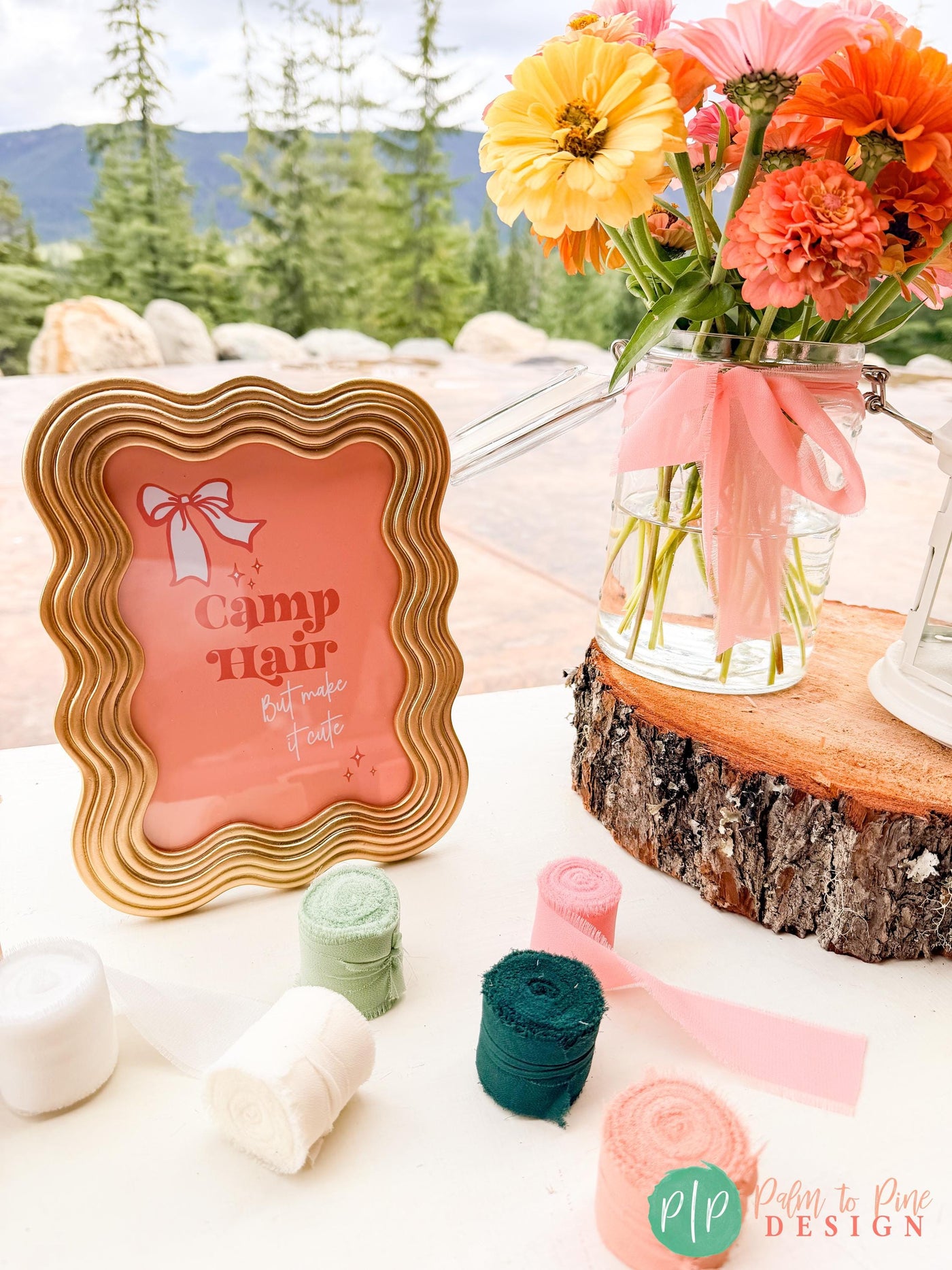 “Camp Hair But Make It Cute printable sign for hairbow station with coral, yellow and pink zinnia flowers and a rustic log round table centerpiece